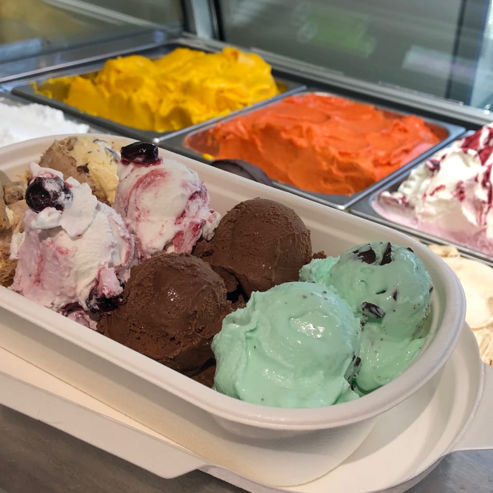 A large bowl of GELATO&Cioccolato gelato with various flavors, including chocolate, mint chip, and berry.