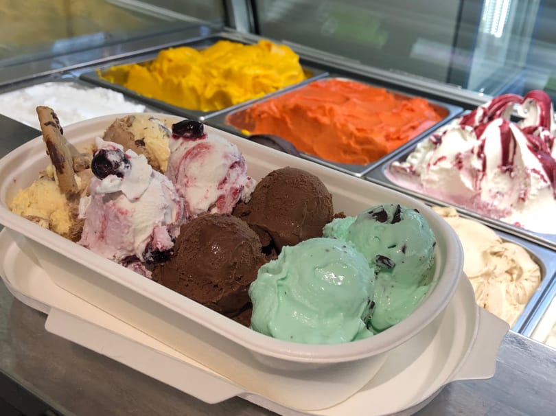 A large bowl of GELATO&Cioccolato gelato with various flavors, including chocolate, mint chip, and berry.